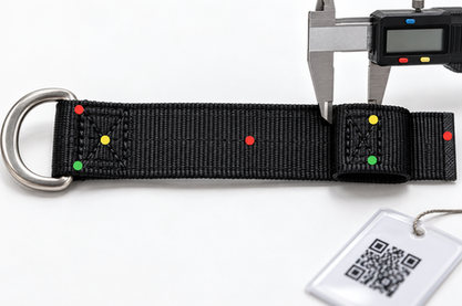 White polyester webbing roll with scissors and measuring tape beside three finished sewn straps with plastic buckles on a workshop table.